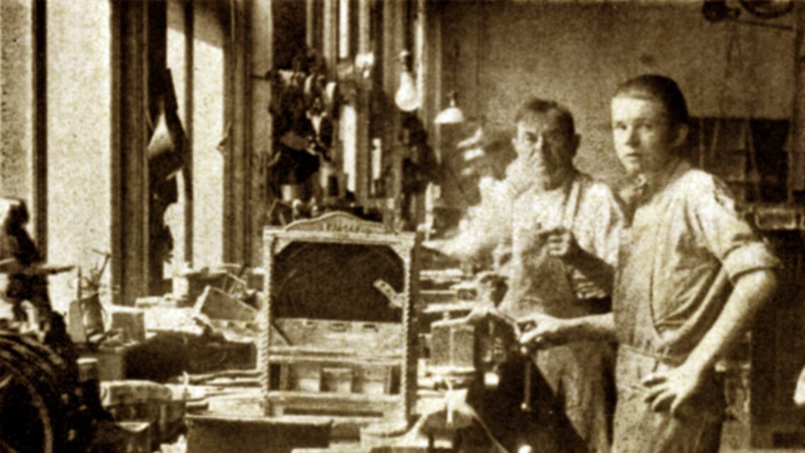 Foto bersejarah Charles Fey (kiri) bersama temannya di workshop tempat mereka membuat mesin slot pertama, Liberty Bell, yang menjadi cikal bakal mesin slot modern.