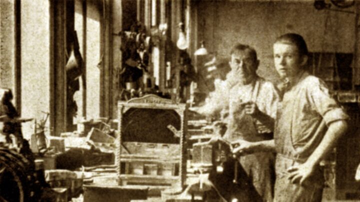 Foto bersejarah Charles Fey (kiri) bersama temannya di workshop tempat mereka membuat mesin slot pertama, Liberty Bell, yang menjadi cikal bakal mesin slot modern.